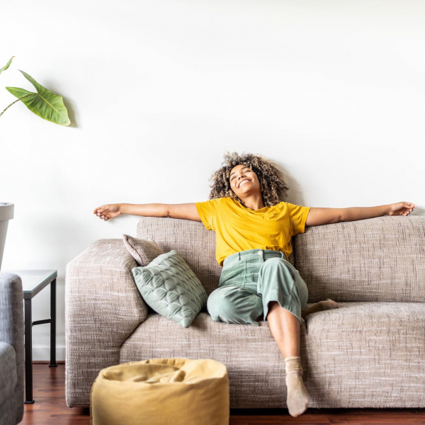Happy afro american woman relaxing on the sofa at home - Smiling girl enjoying day off lying on the couch - Healthy life style, good vibes people and new home concept